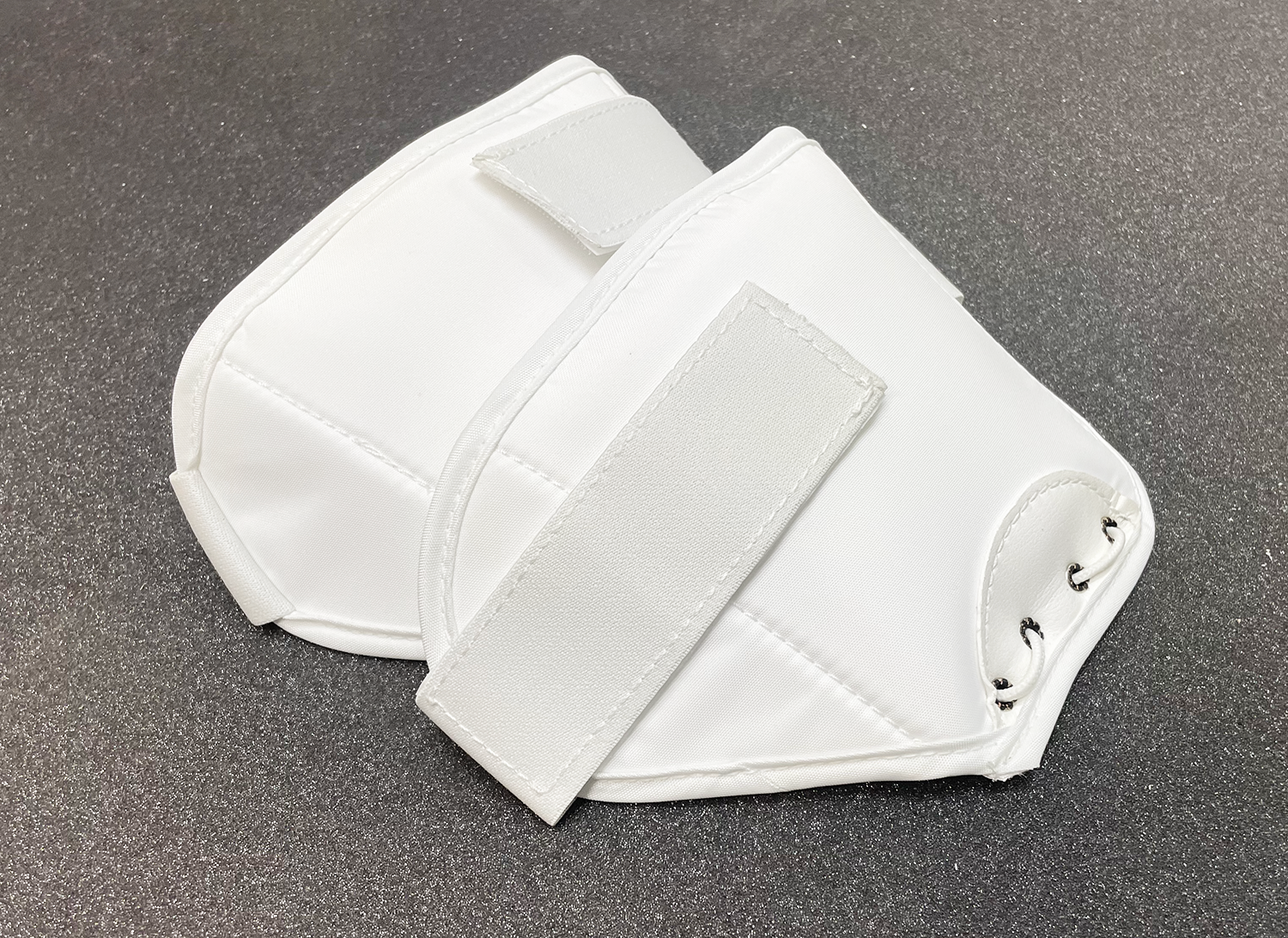 Angled profile of two white thigh guards